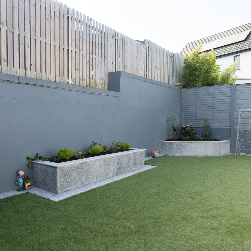 Artificial grass lawn beside paving and raised garden planters